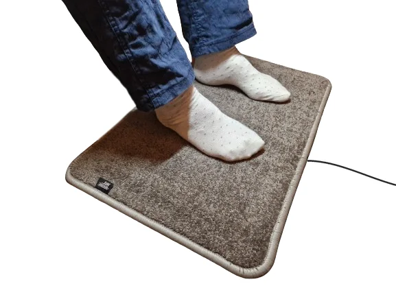 Taupe verwarmde voetenmat Excellent van De WarmeMat™ met voeten in sokken, hoogpolig en 35~45°C warm