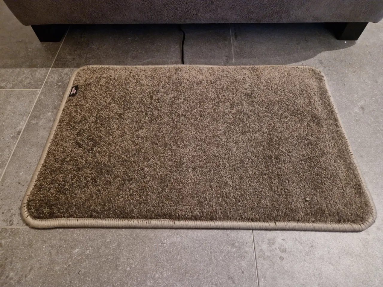 Taupe verwarmde voetenmat voor de bank in de woonkamer tegen koude voeten